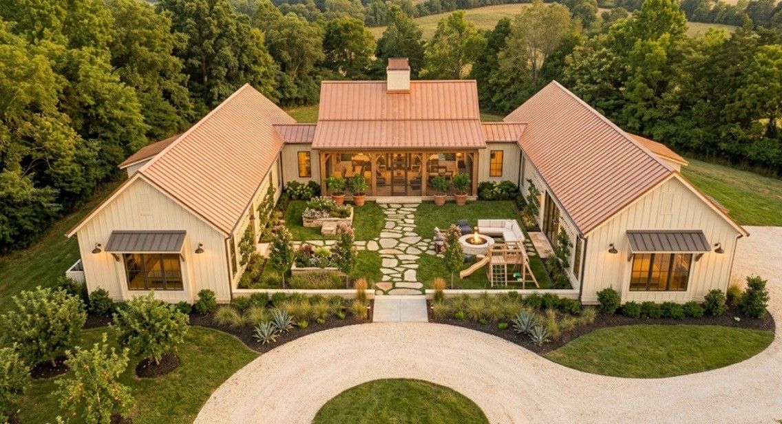 Aerial view of a U-shaped courtyard estate with copper roofs, a stone-path garden, fire pit and a circular gravel drive.