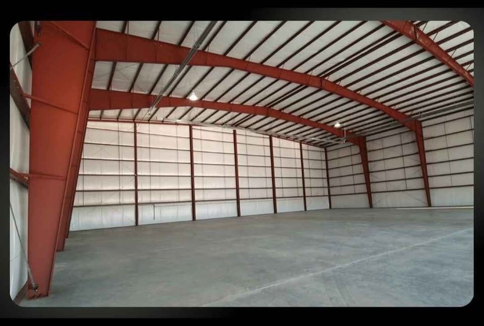 Inside a finished clear span: red tapered frames, white liner panels and a concrete floor.