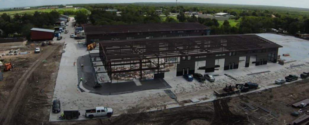 Aerial view of a long red iron frame set on a new pad, with trucks and crews around it.