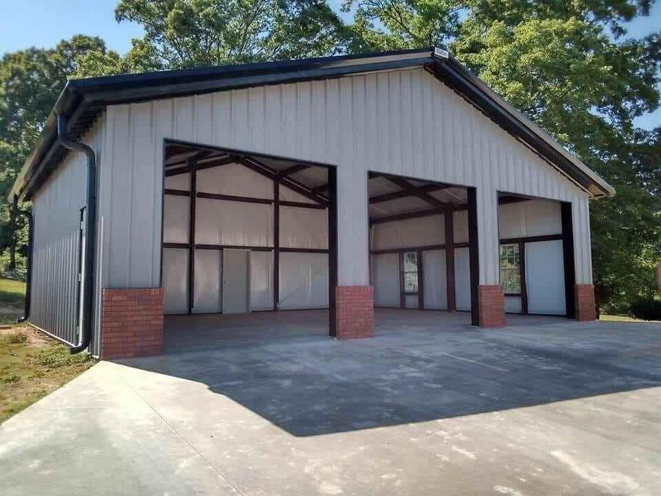 A finished steel building with three open bays, brick bases and a concrete apron.