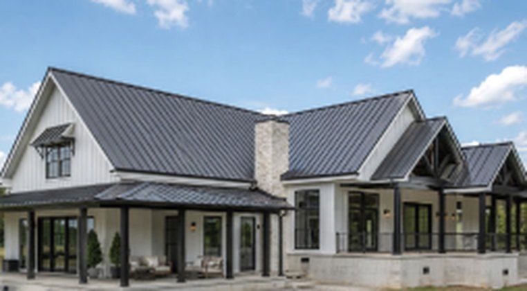 Finished white farmhouse with dark metal roof and covered porch